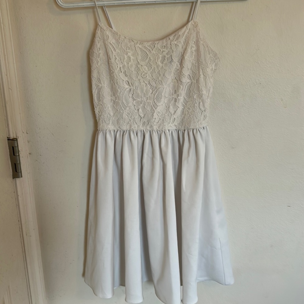 White dress, floral up top, skirt pleated.